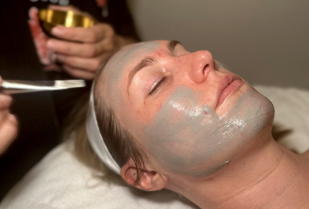 Patient getting a facial mask painted on during acne treatment