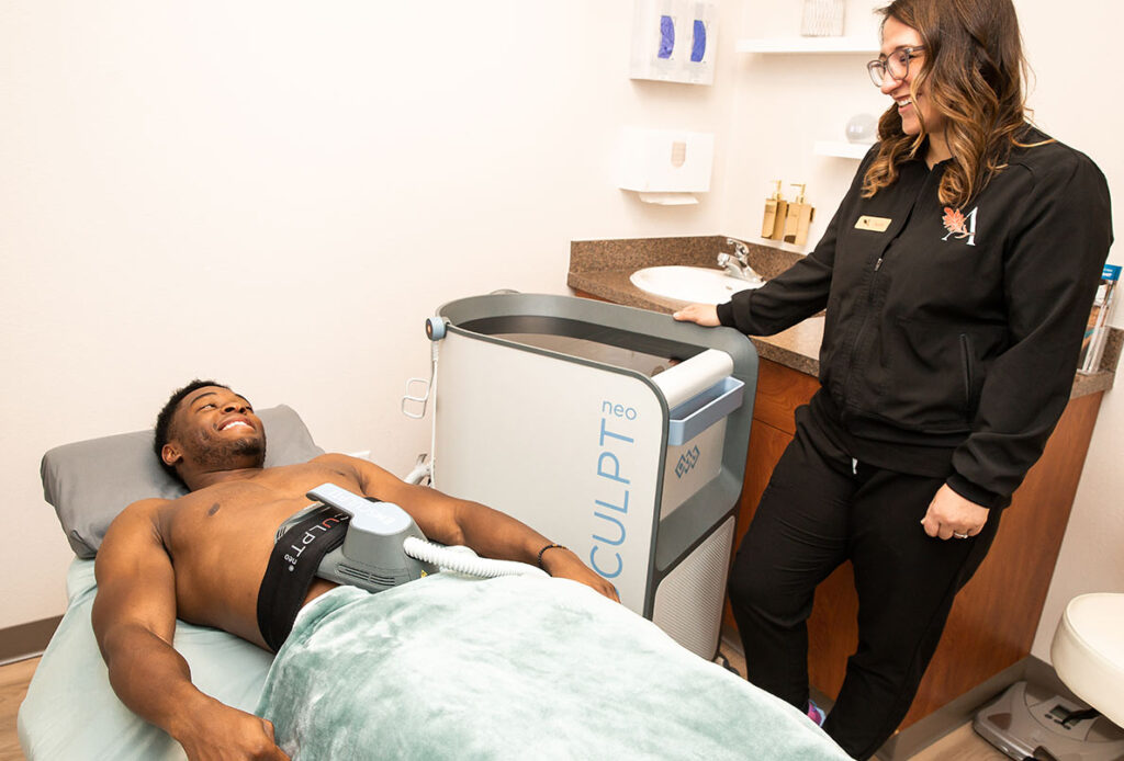 Man receiving Emsculpt treatment for body strength and function with technician