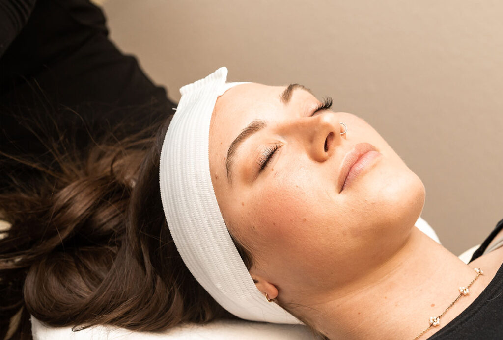 Woman with headband and eyes closed, waiting for MOXI skin treatment