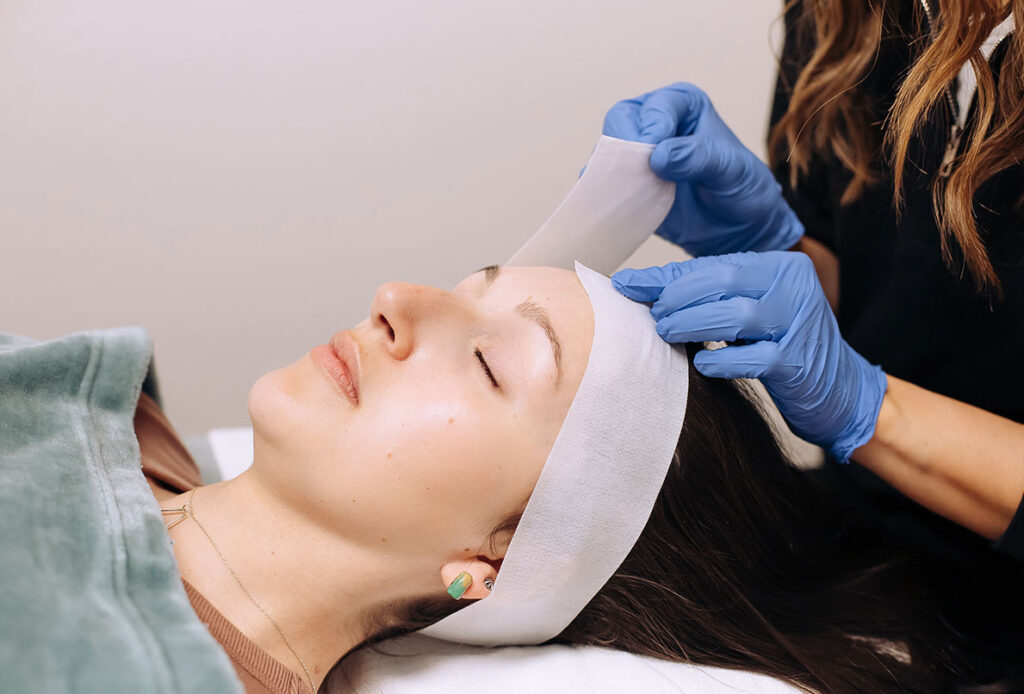 Technician at Ascent Med Spa wrapping a headband around a patient before a facial procedure
