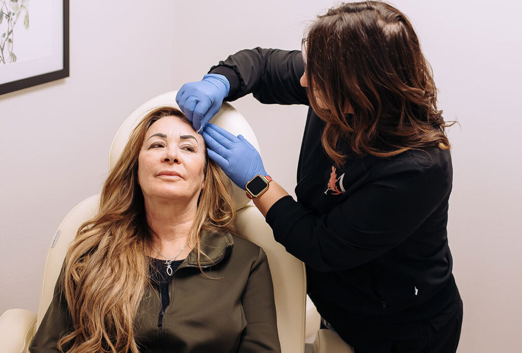 Technician wiping patient's face before she receives Sculptra at Ascent Med Spa in Laramie, WY