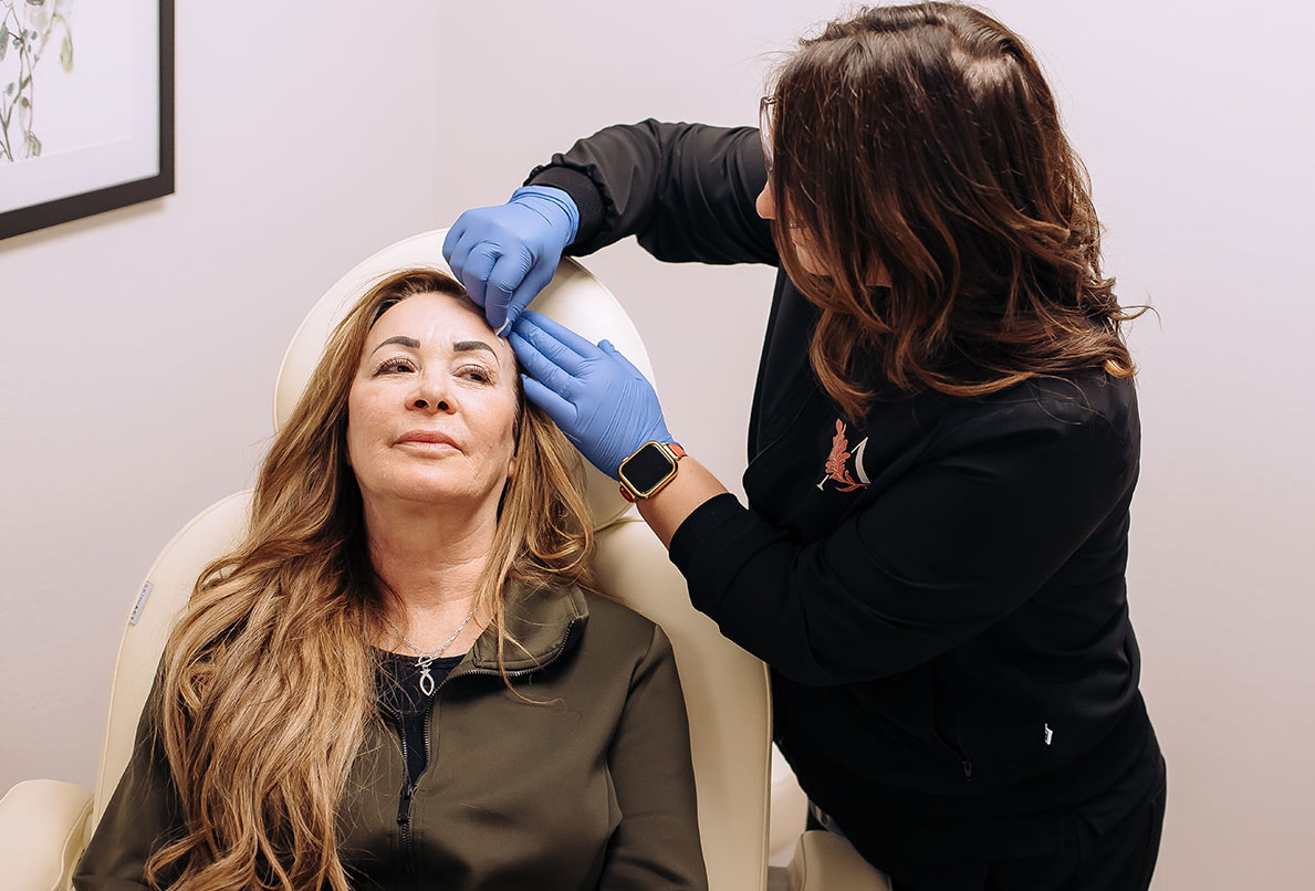 Technician wiping patient's face before she receives Sculptra at Ascent Med Spa in Laramie, WY